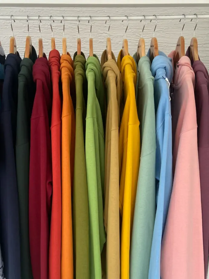 a rack of colorful shirts hanging on clothes pins