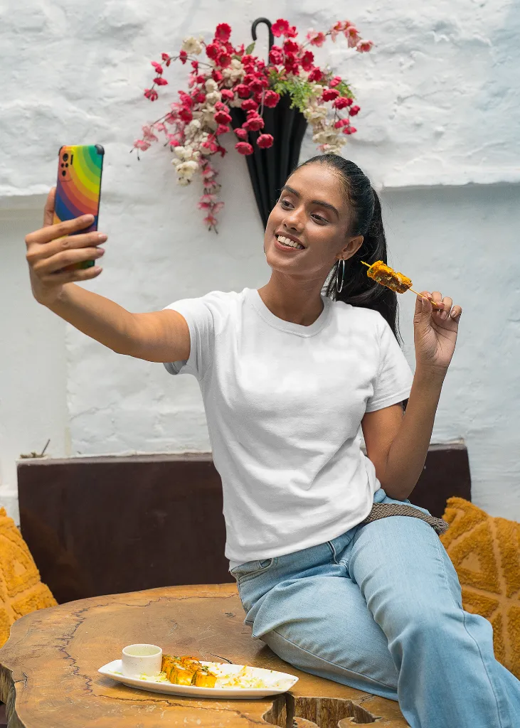 gildan-t-shirt-mockup-of-a-happy-woman-taking-a-selfie-and-eating-indian-food-m30294 (2).webp