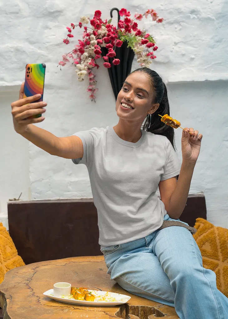 gildan-t-shirt-mockup-of-a-happy-woman-taking-a-selfie-and-eating-indian-food-m30294 (5).webp